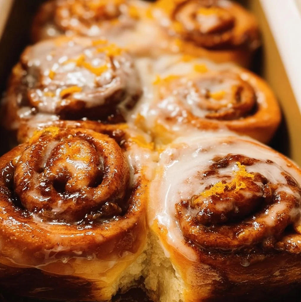 Freshly baked orange cinnamon rolls with icing on a plate