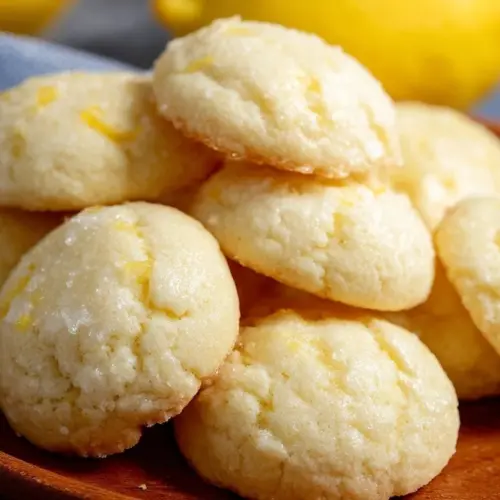 Delicious Lemon Ricotta Cookies on a plate with a lemon wedge