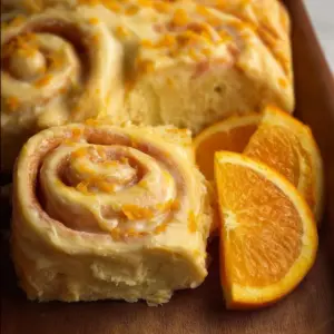 Homemade orange rolls topped with icing on a plate
